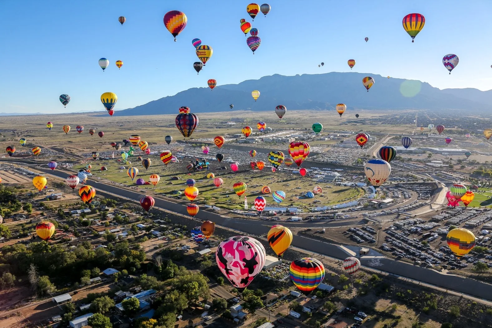 Hundreds of hot air balloons rising over the Sandia Mountains at the Albuquerque International Balloon Fiesta