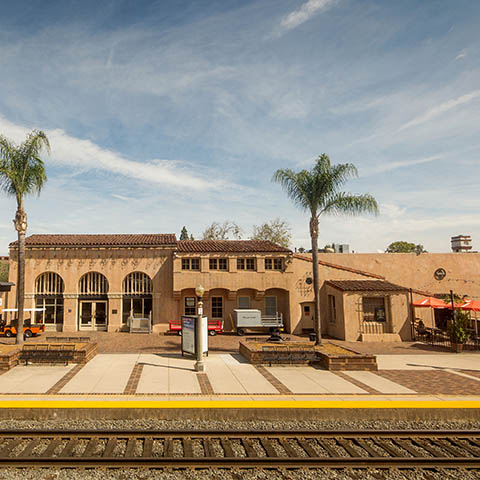 The historic Fullerton Train Depot and Transportation Center building with palm trees and rail platform in north Orange County