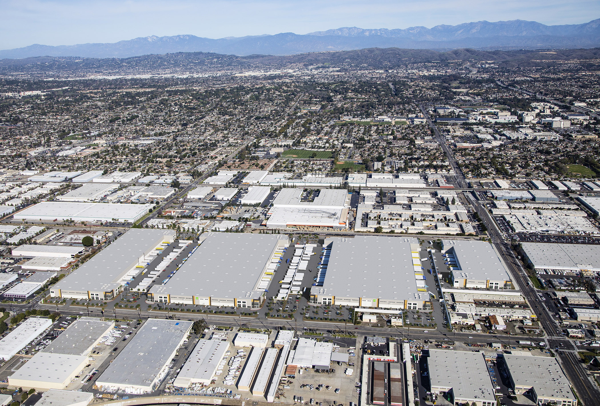 Aerial view of the Fullerton warehouse and logistics corridor with distribution buildings and the San Gabriel foothills behind