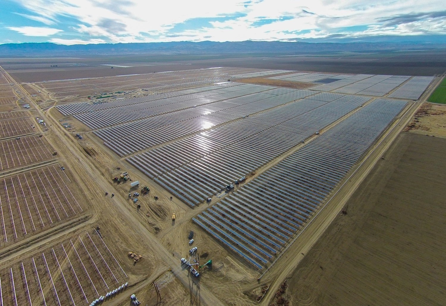 Aerial view of a large desert solar farm under construction near the Inland Empire with crews and equipment