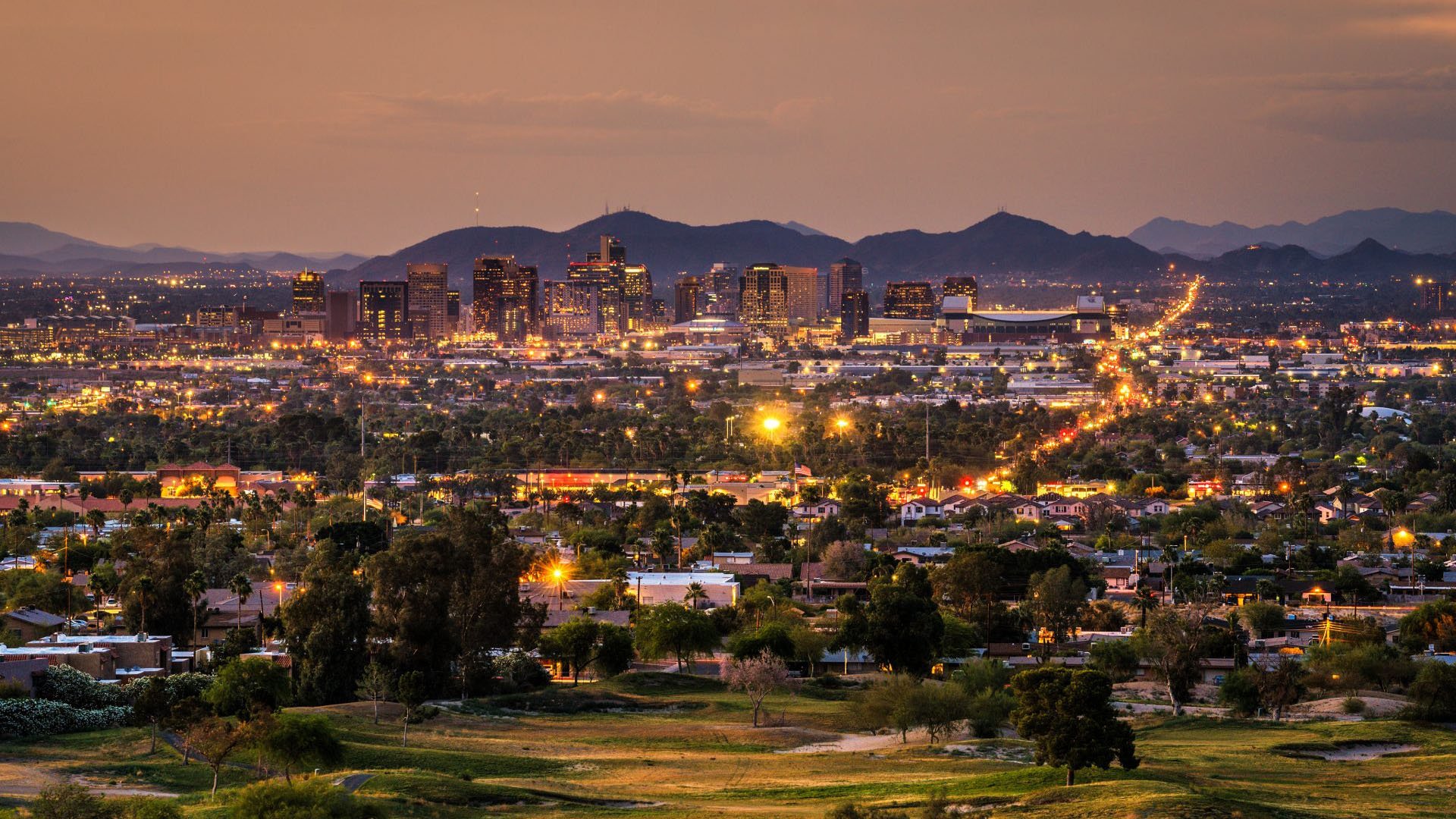 Aerial view of an East Valley Arizona metro skyline at dusk with desert mountains behind