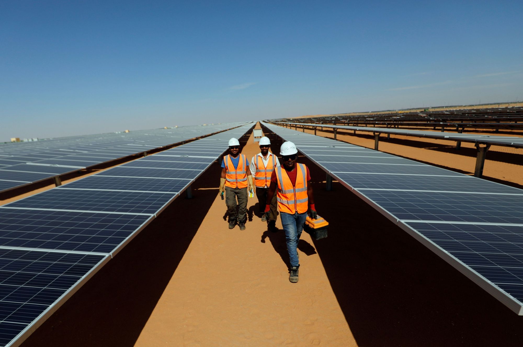 Outdoor solar installation crew in high-visibility vests working a desert field near Mesa with on-site water access