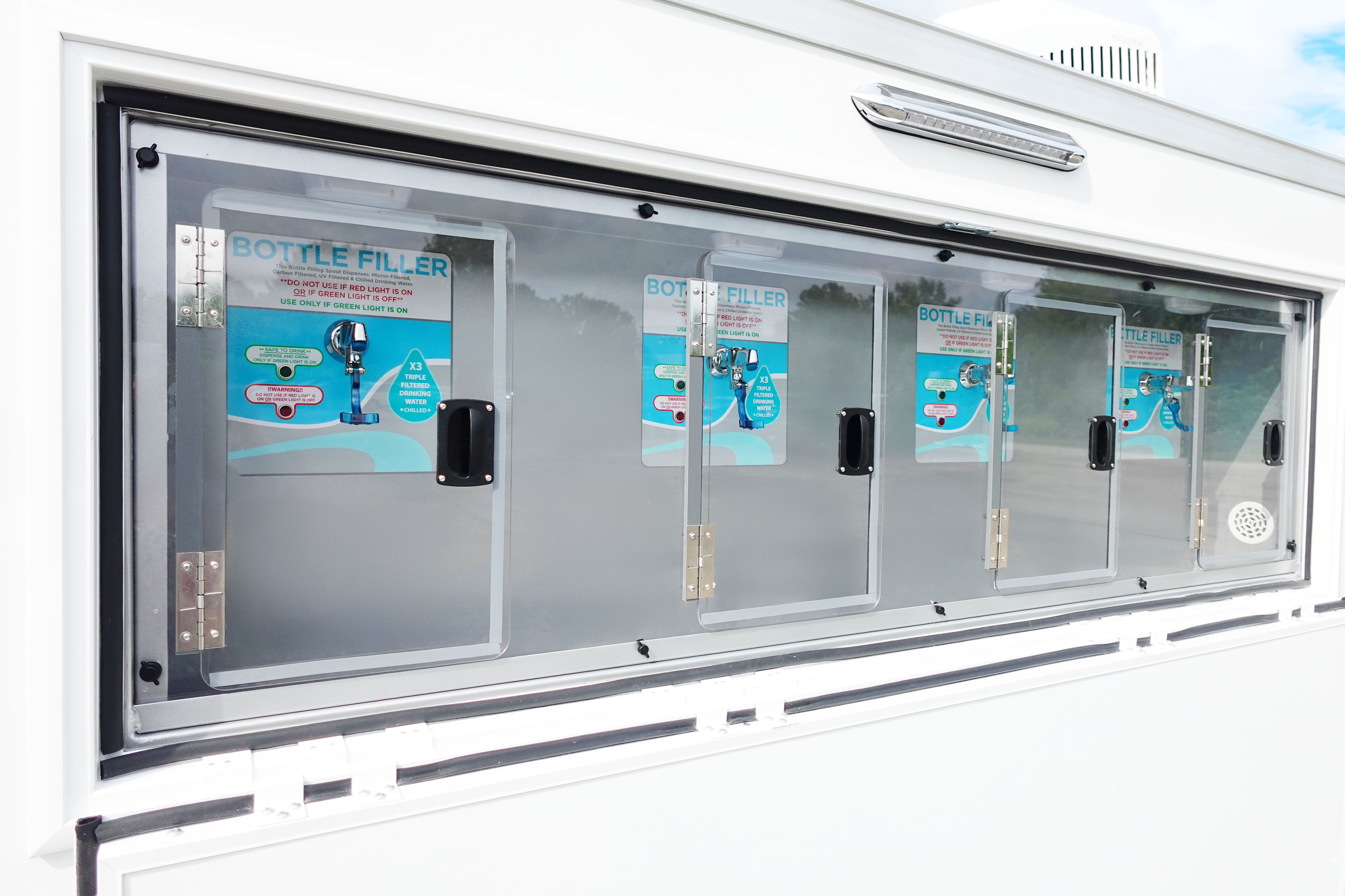 Close-up of four chilled, four-stage filtered bottle filling stations on a Texas mobile water trailer