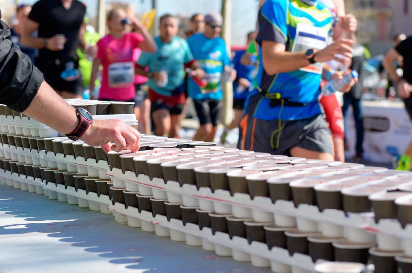 Runners refilling at outdoor water stations during a Tucson-area race in the sun