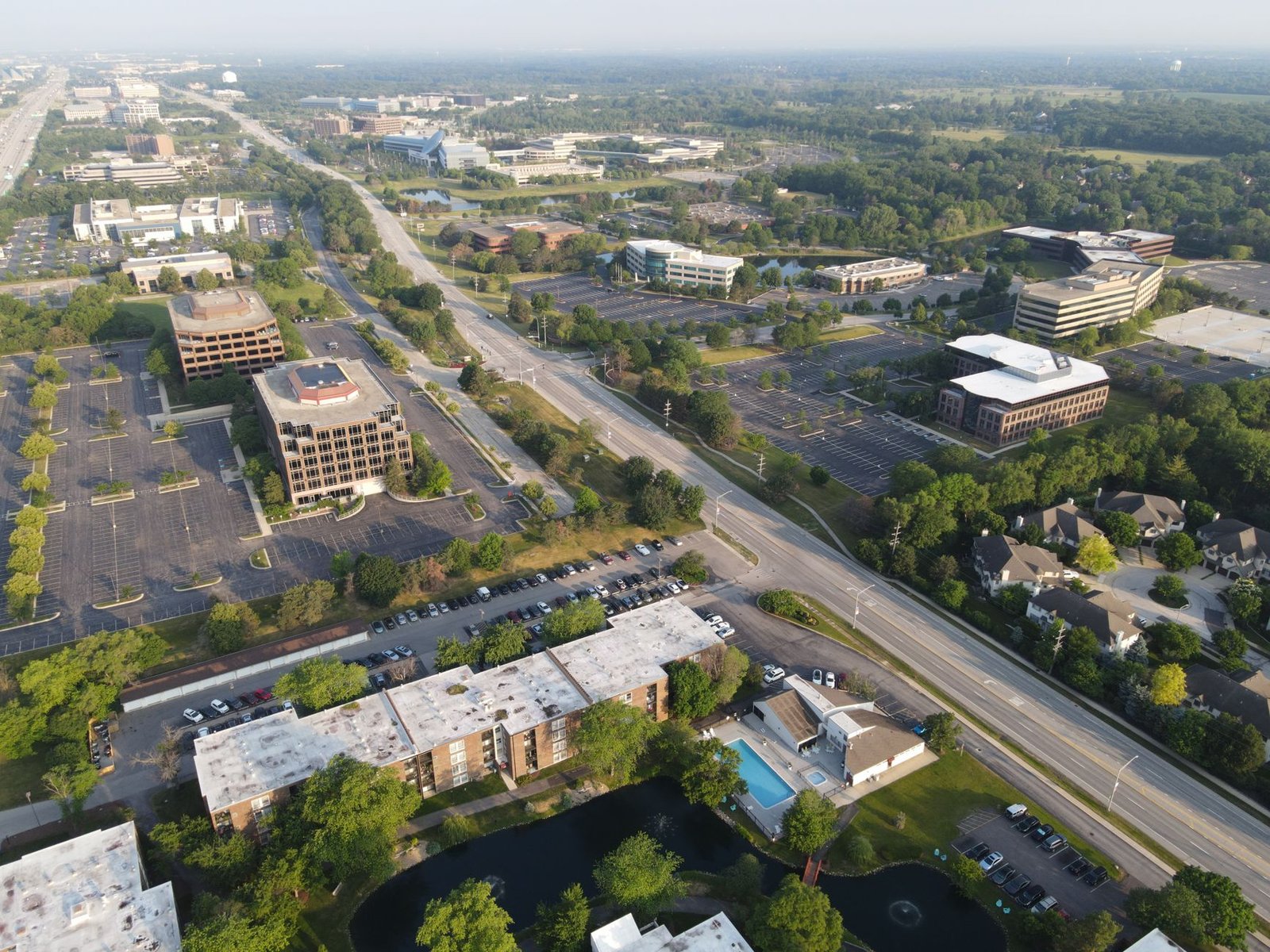 An aerial view of a suburban office park with parking lots and mature trees