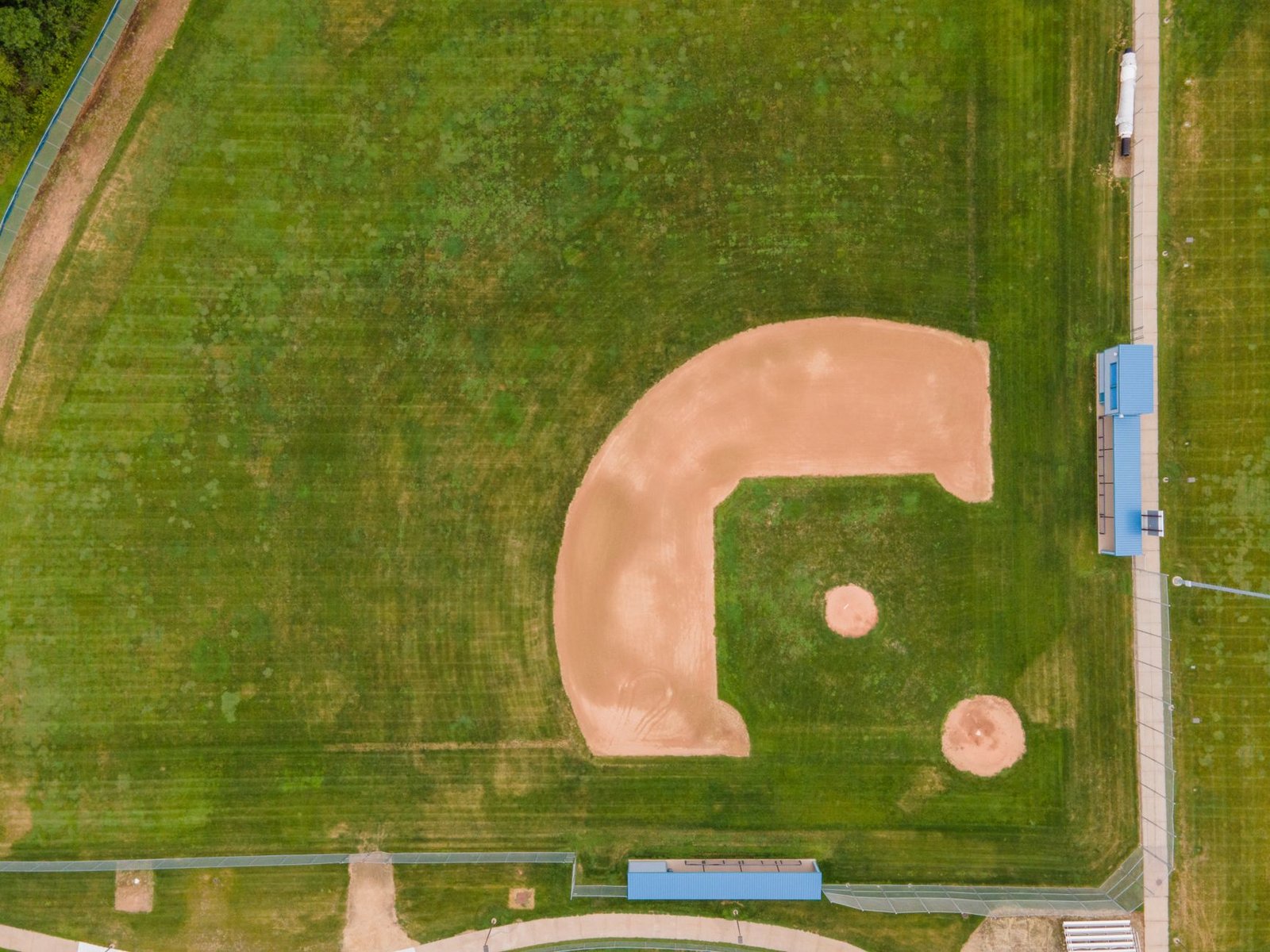 An aerial view of an empty baseball diamond and dugouts at a community sports field